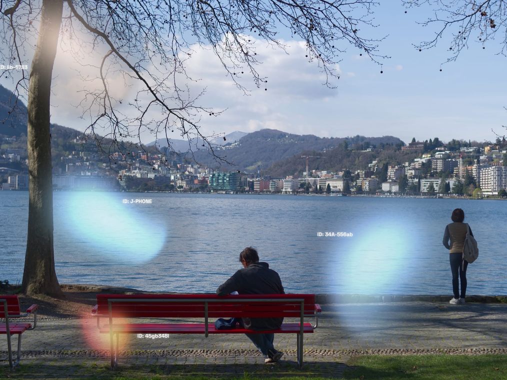 An ELEN capture of a lakeside promenade: pale spectral blobs of different sizes drift over the scene, each tagged with an anonymized identifier.