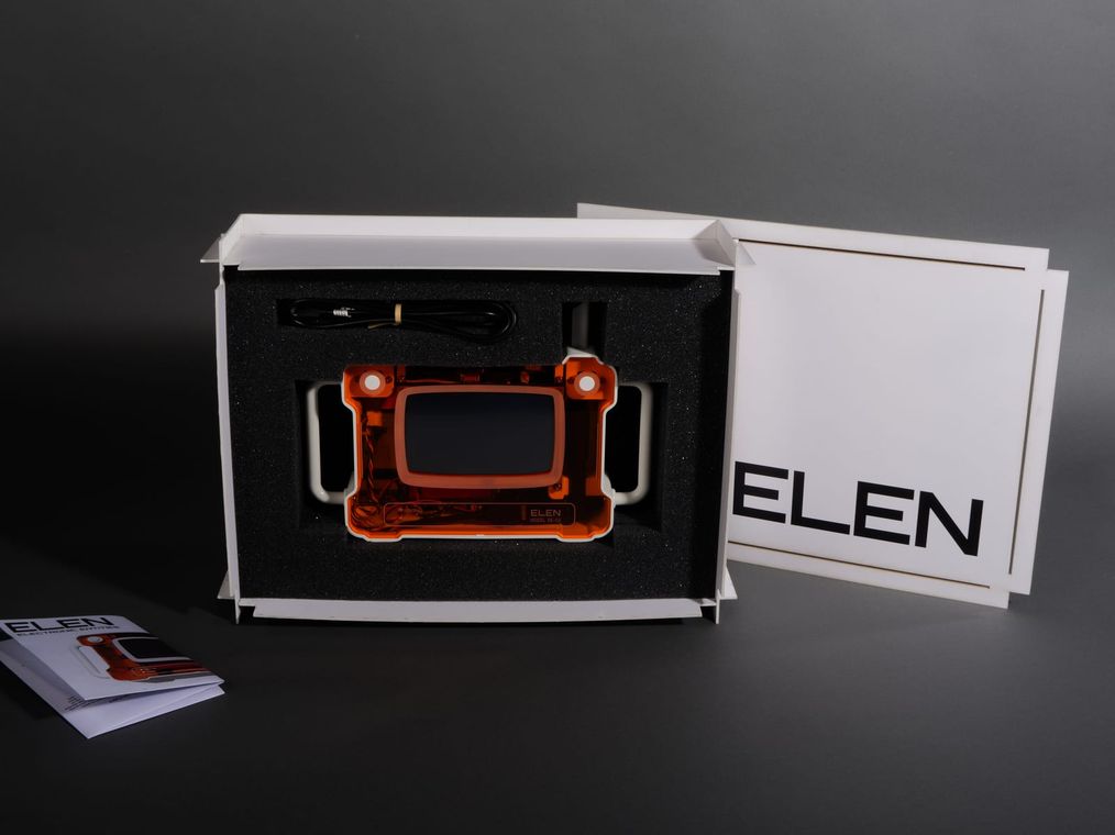 ELEN in its open packaging: the device nestled in foam inside the interlocking white box, with its antenna and a printed brochure.