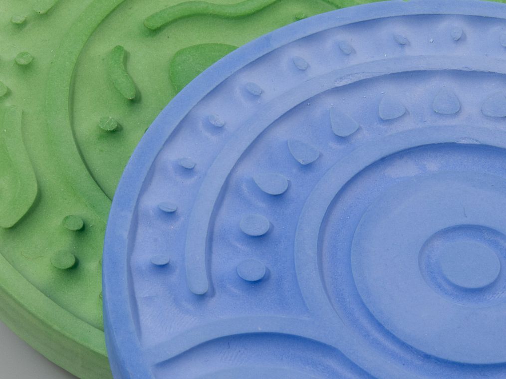 A close-up of a plaster disk showing its raised texture and tinted surface, read by touch.