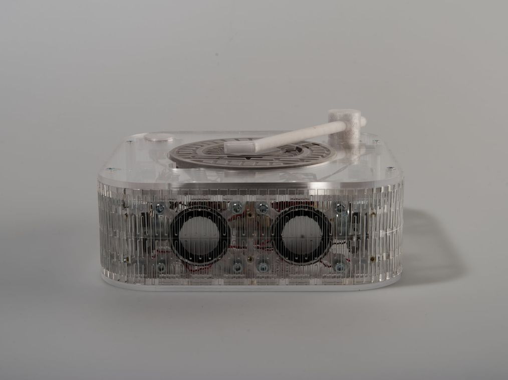 The full-perimeter live-hinge belt letting rigid acrylic bend around the whole object while staying acoustically open.