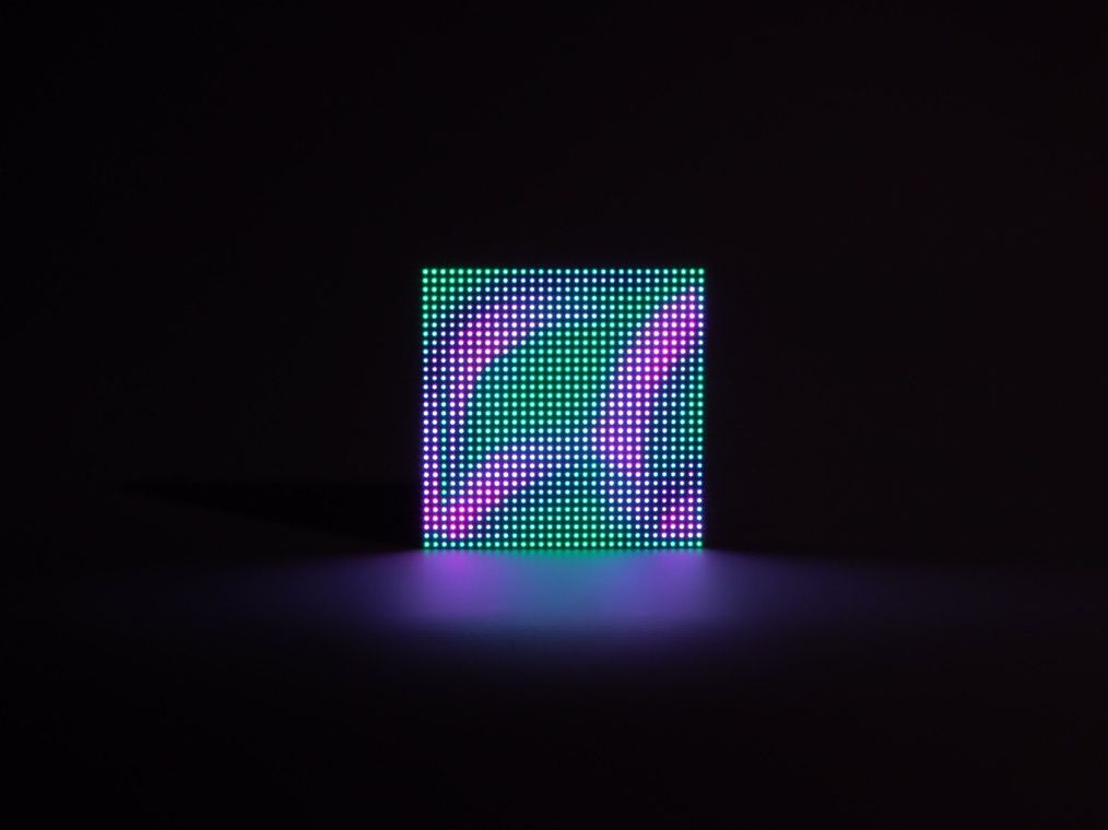 A single pond where green, blue and magenta light mix across the grid, a received drop briefly blending its color into the local pond.