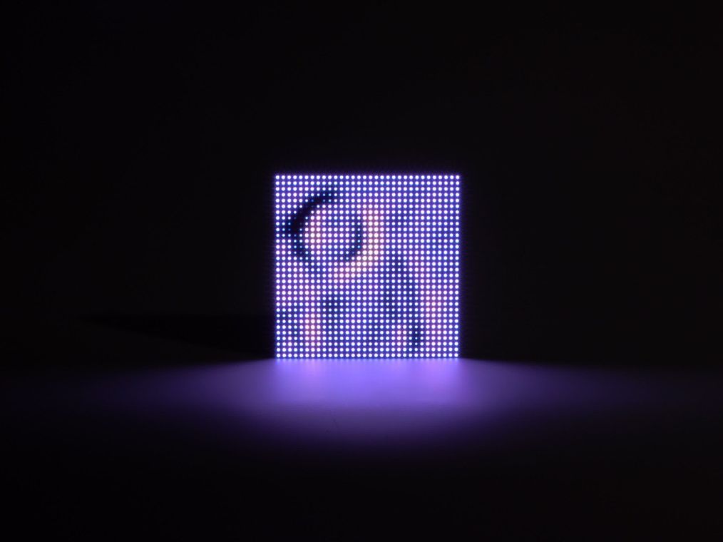 The LED matrix showing violet light radiating outward just after a drop lands, the individual pixels of the 32×32 grid clearly visible.