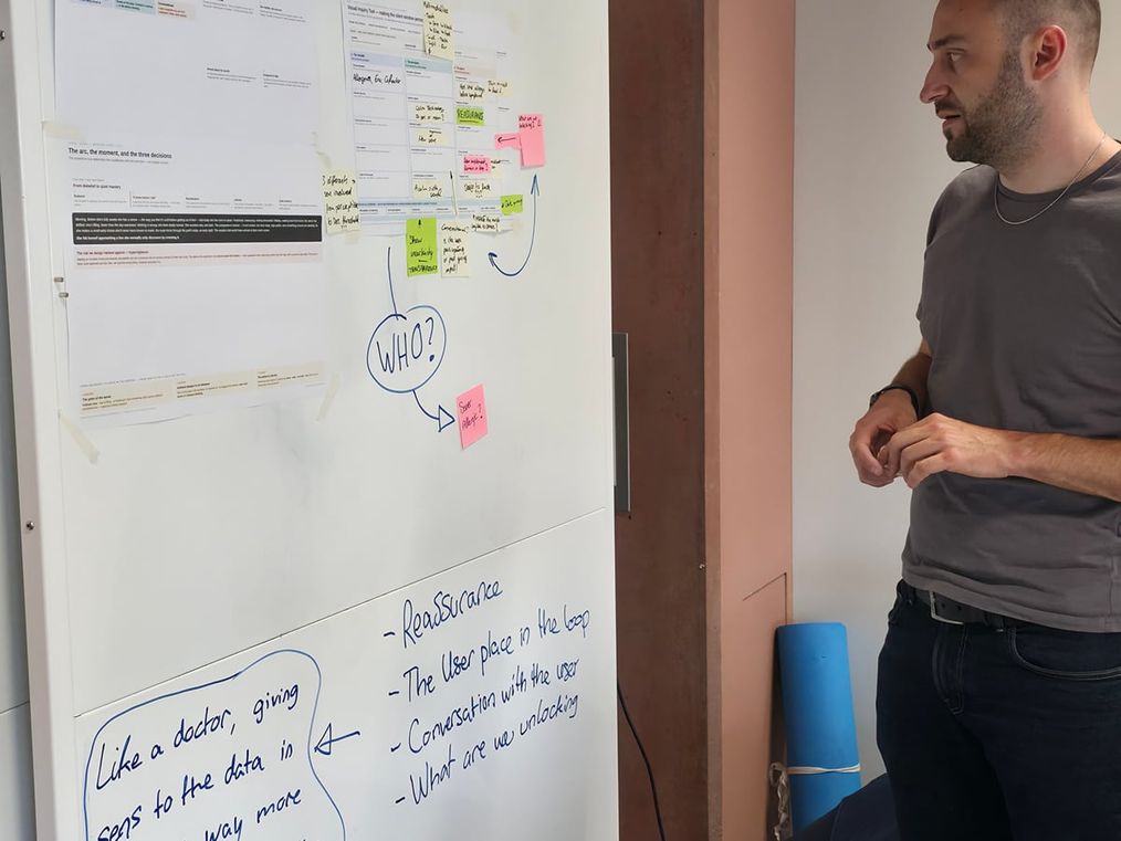 A teammate standing at the project's whiteboard wall during the five-week module, sticky notes and sketches behind.