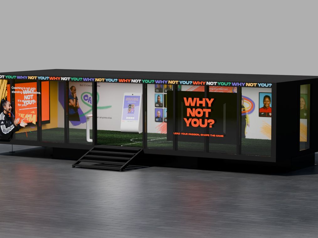 A 3D render of the Euro 2025 trailer booth: a long black stand wrapped in repeating Why not you? type and screens of coaches, with Lead your passion, shape the game on the end panel.