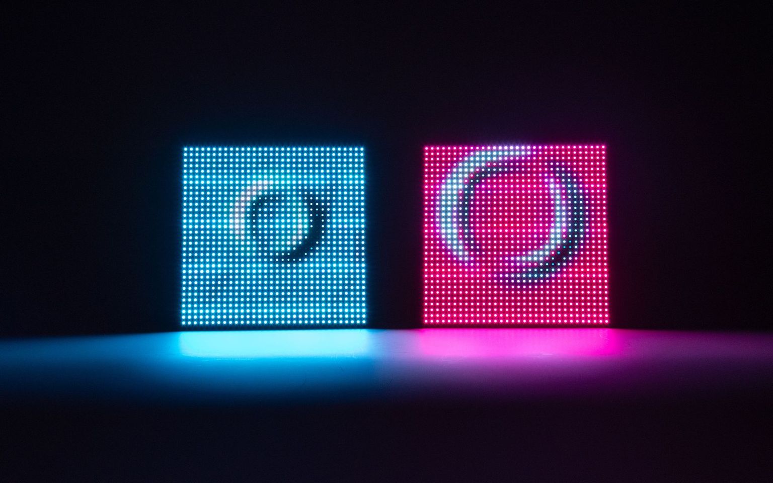 Two connected Meeting Pond units standing side by side, one glowing blue and the other pink, each showing ripples across a 32×32 LED grid.