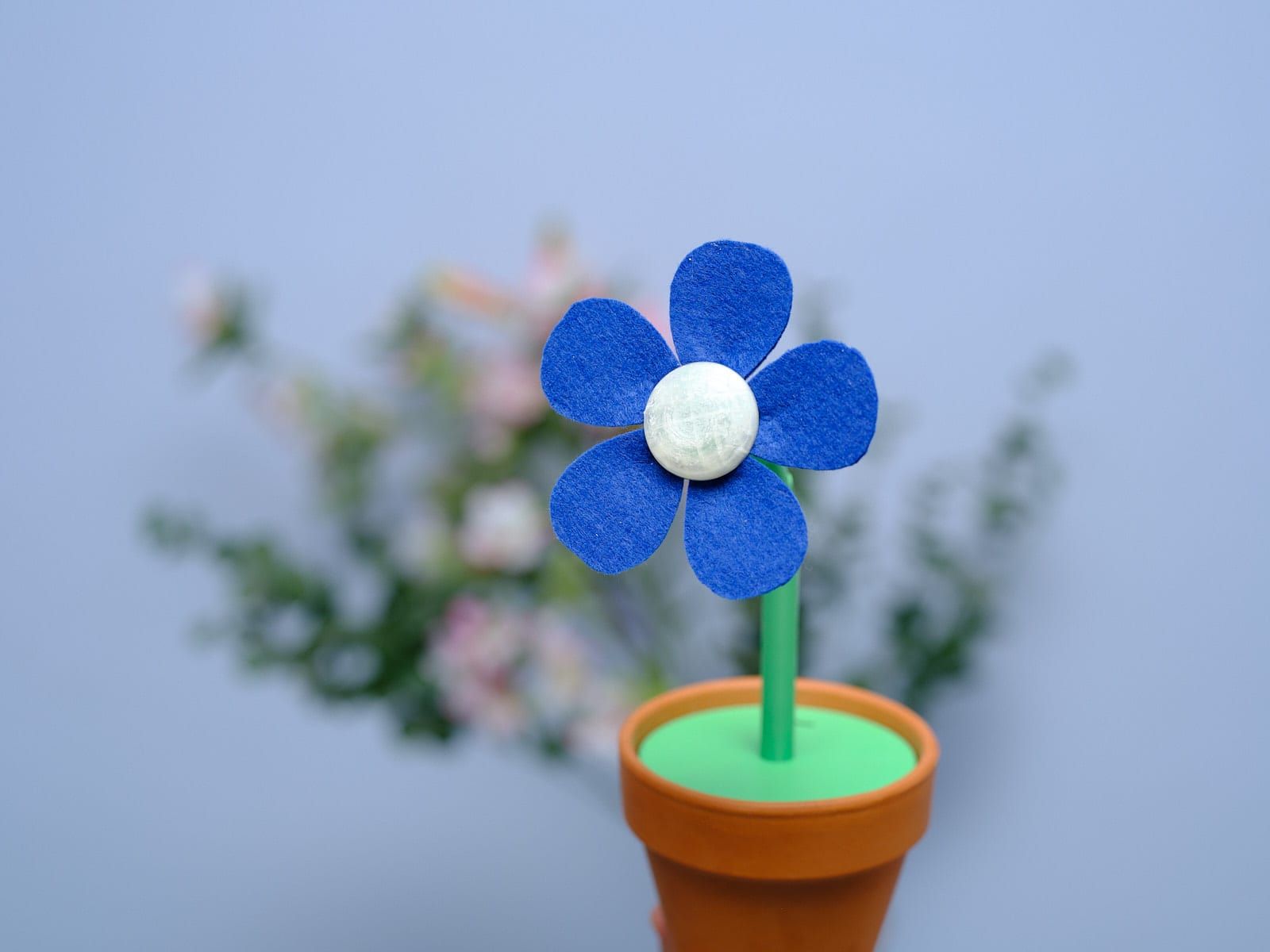 Close-up of the flower head: cobalt felt petals around the pale 3D-printed center that houses the light.